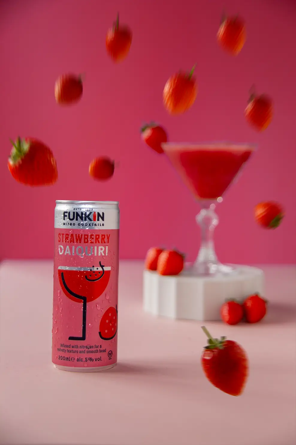 strawberry daiquiri can with coctail glass in the background